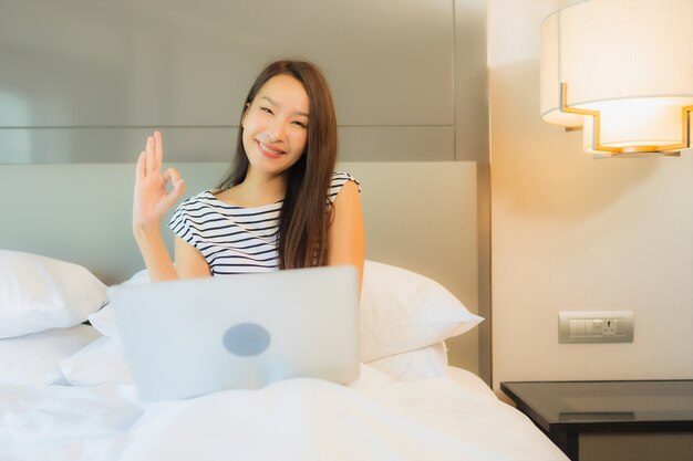 Portrait beautiful young asian woman use computer laptop on bed in bedroom interior