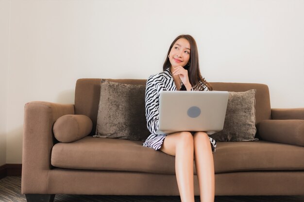 Portrait beautiful young asian woman use computer laptop on sofa in living room interior area