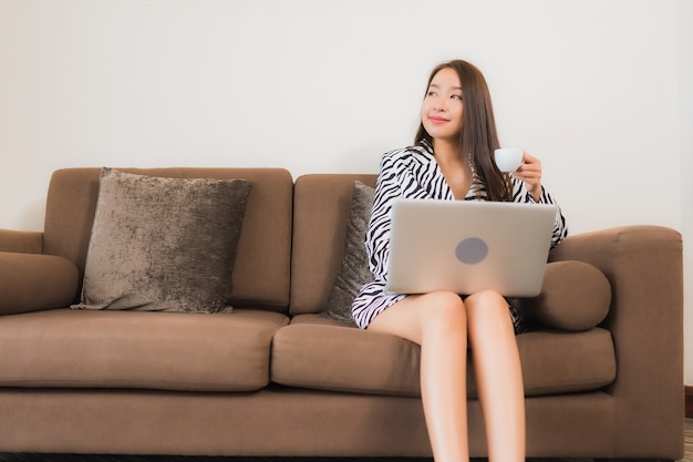 Portrait beautiful young asian woman use computer laptop on sofa in living room interior area