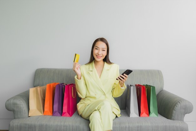 Portrait beautiful young asian woman use computer laptop with credit card for online shopping on sofa in living room interior