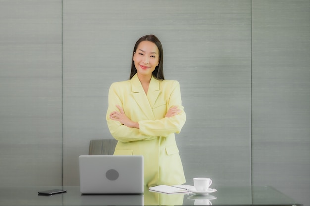 Portrait beautiful young asian woman use computer laptop with smart mobile phone on working table at interior room