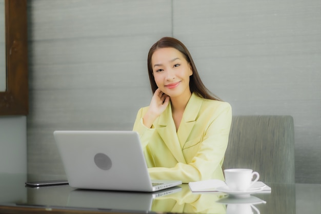 Portrait beautiful young asian woman use computer laptop with smart mobile phone on working table at interior room