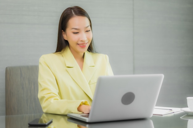 Portrait beautiful young asian woman use computer laptop with smart mobile phone on working table at interior room