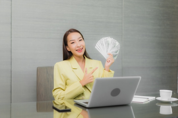 Free photo portrait beautiful young asian woman use computer laptop with smart mobile phone on working table at interior room