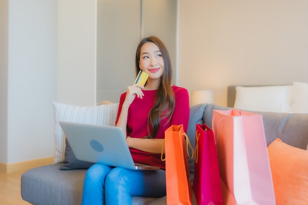 Foto gratuita computer portatile di uso della bella giovane donna asiatica del ritratto con la carta di credito