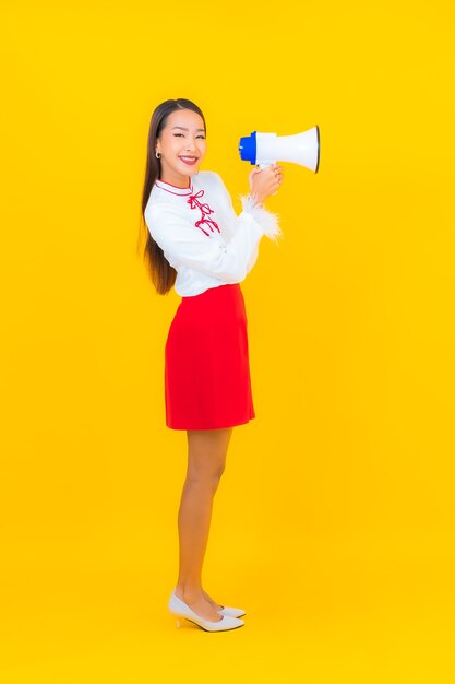 Portrait beautiful young asian woman use megaphone on yellow