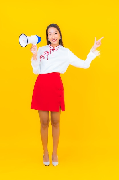 Portrait beautiful young asian woman use megaphone on yellow