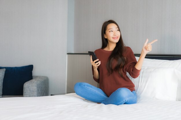 Portrait beautiful young asian woman use smart mobile phone on bed in bedroom interior