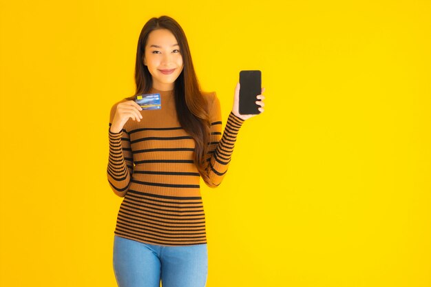 온라인 쇼핑을위한 신용 카드로 세로 아름 다운 젊은 아시아 여자 사용 스마트 휴대 전화 또는 핸드폰