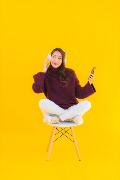 肖像画美しい若いアジアの女性はスマート携帯電話を使用して音楽を聴く