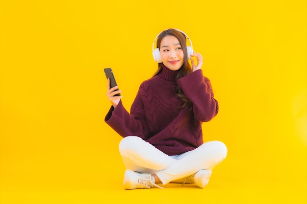 Мобильный телефон пользы женщины портрета красивой молодой азиатской умный слушает музыка