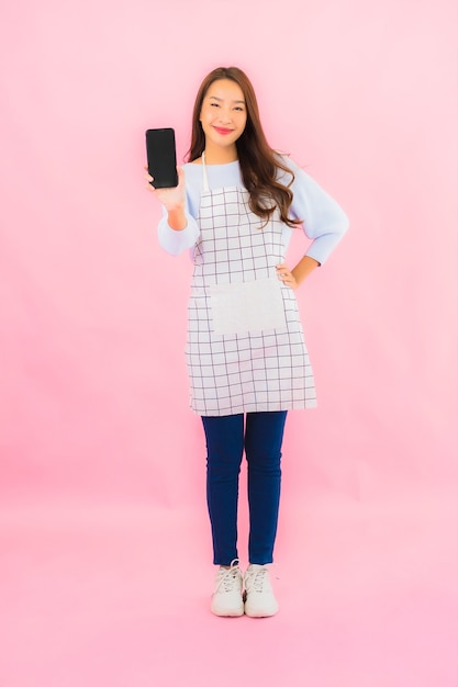 세로 아름 다운 젊은 아시아 여자 핑크 절연 벽에 스마트 휴대 전화를 사용