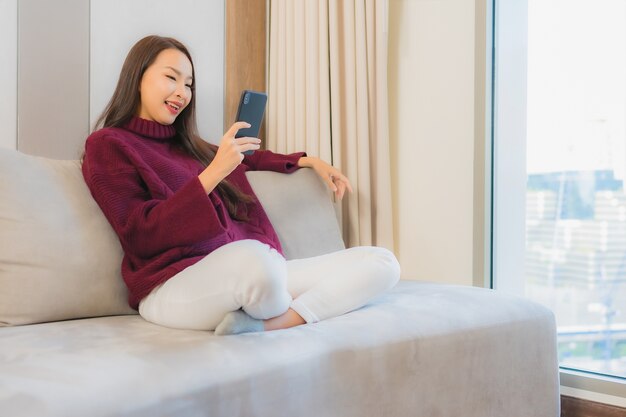 Portrait beautiful young asian woman use smart mobile phone on sofa in living room interior