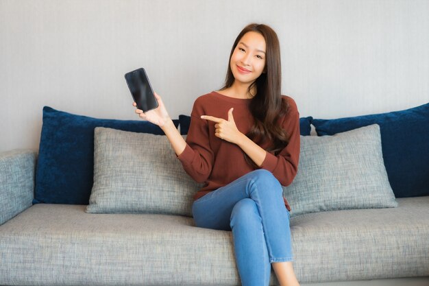 Portrait beautiful young asian woman use smart phone on sofa in living room interior