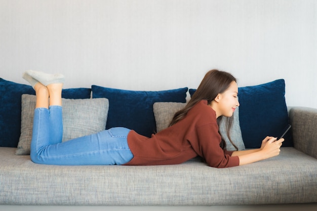 Portrait beautiful young asian woman use smart phone on sofa in living room interior