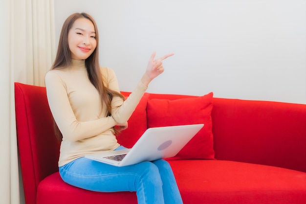 Portrait of beautiful young asian woman uses computer laptop on sofa in living room interior