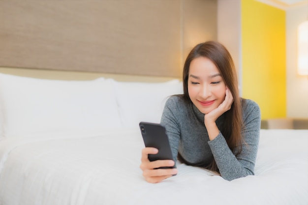 Portrait of beautiful young asian woman uses smartphone on bed