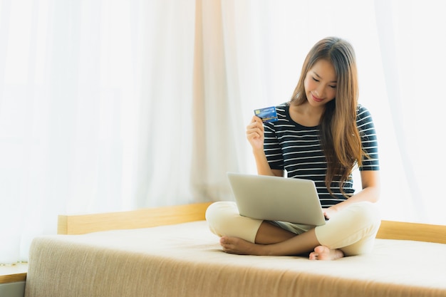 Portrait beautiful young asian woman using computer notebook or laptop with credit card for shopping