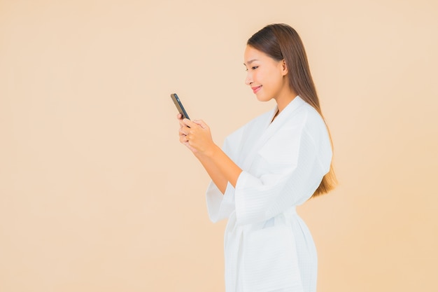 베이지 색에 스마트 휴대 전화를 사용 하여 세로 아름 다운 젊은 아시아 여자