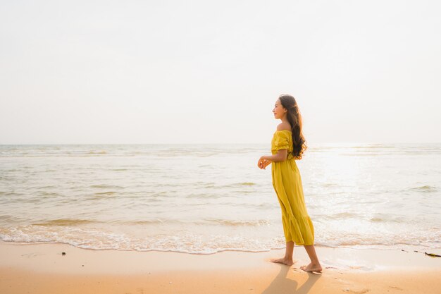 Прогулка женщины портрета красивая молодая азиатская на пляже и океане моря с улыбкой счастливой ослабляет