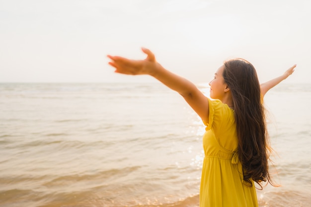 Portrait beautiful young asian woman walk on the beach and sea ocean with smile happy relax