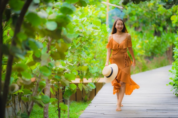 La bella giovane camminata asiatica della donna del ritratto sul percorso cammina nel giardino