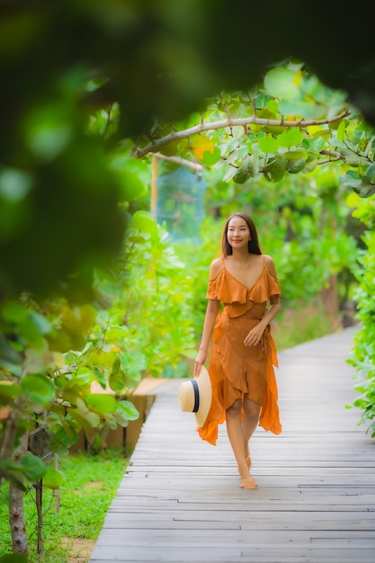 La bella giovane camminata asiatica della donna del ritratto sul percorso cammina nel giardino