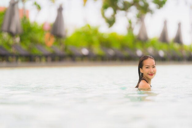 肖像画美しい若いアジア人女性はホテルのリゾート地のスイミングプールの周りビキニを着るほぼ海海ビーチ
