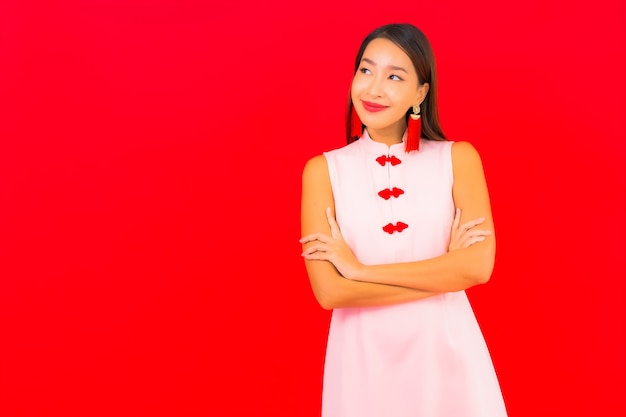 肖像画美しい若いアジアの女性は赤い壁に旧正月の服を着る