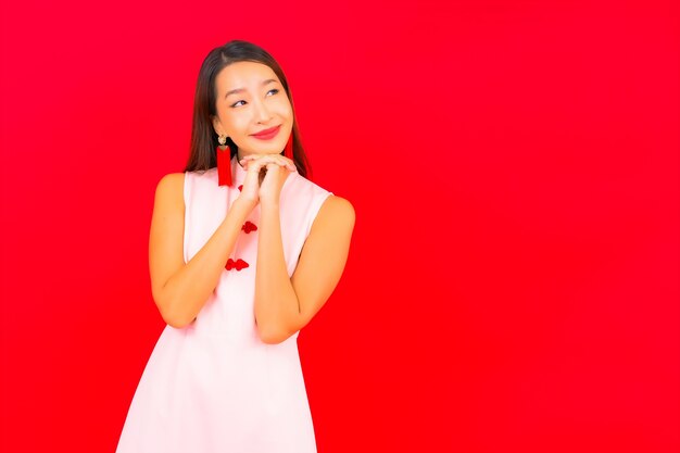 Portrait beautiful young asian woman wear chinese new year clothing on red wall