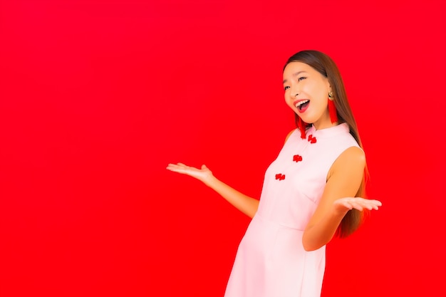 Portrait beautiful young asian woman wear chinese new year clothing on red wall