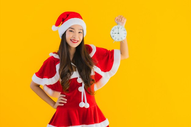 肖像画美しい若いアジアの女性はクリスマスの服と帽子ショー時計を着用します