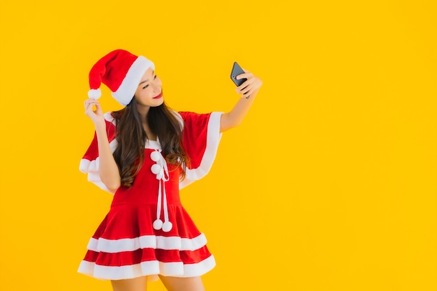 肖像画美しい若いアジアの女性はクリスマスの服を着て、帽子は携帯電話を使用します