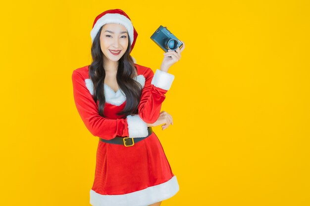 노란색에 카메라와 함께 크리스마스 의상을 입고 초상화 아름다운 젊은 아시아 여자