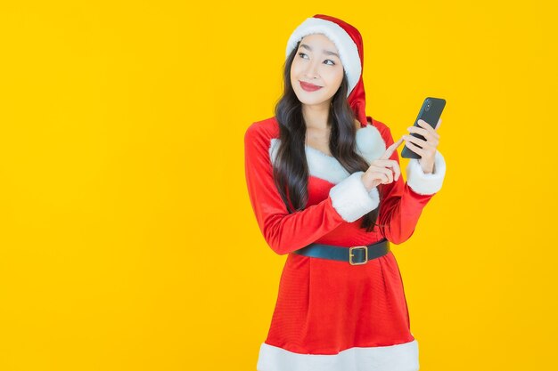 肖像画美しい若いアジアの女性は黄色の携帯電話でクリスマスの衣装を着る