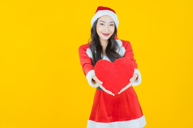 Portrait beautiful young asian woman wear christmas costume with pillow heart on yellow