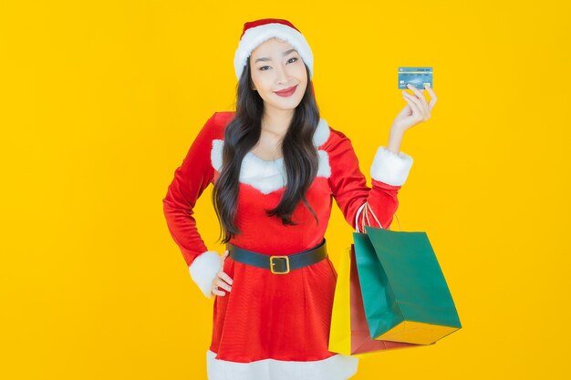 肖像画美しい若いアジアの女性は黄色の買い物袋とクリスマスの衣装を着る