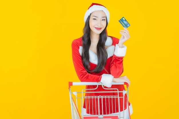 肖像画美しい若いアジアの女性は黄色のショッピングカートでクリスマスの衣装を着る