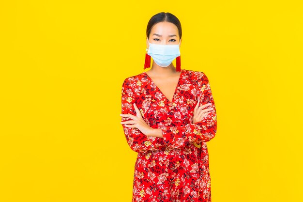 노란색 벽에 코로나 바이러스 또는 covid19를 보호하기 위해 초상화 아름 다운 젊은 아시아 여자 착용 마스크