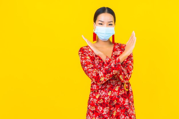 Portrait beautiful young asian woman wear mask for protect corona virus or covid19 on yellow wall