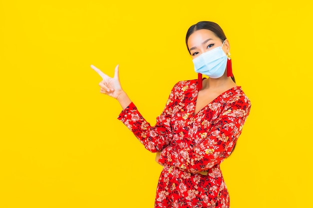 Portrait beautiful young asian woman wear mask for protect corona virus or covid19 on yellow wall