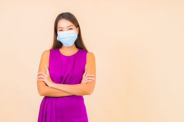 肖像画美しい若いアジアの女性は、色の背景にcovid19またはコロナウイルスから保護するためのマスクを着用してください
