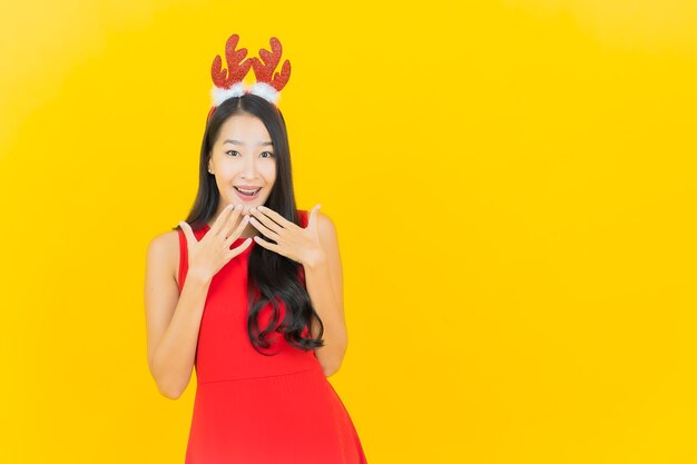 Free photo portrait beautiful young asian woman wear santa hat or hairband on yellow wall