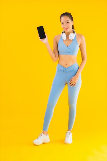 肖像画の美しい若いアジアの女性は、スマートフォンでスポーツウェアを着用します。