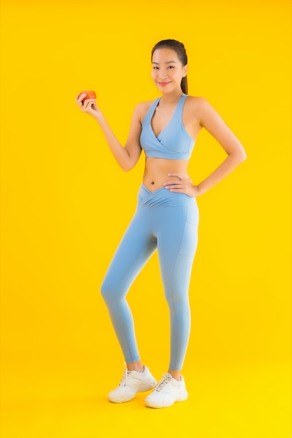 肖像画の美しい若いアジア女性は黄色の運動の準備ができて体操服を着る
