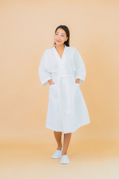 베이지 색에 미소로 목욕 가운을 입고 초상화 아름 다운 젊은 아시아 여자