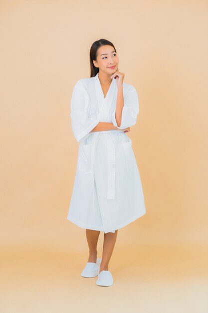 Portrait beautiful young asian woman wearing bathrobe with smile on beige