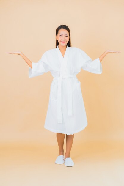 Portrait beautiful young asian woman wearing bathrobe with smile on beige