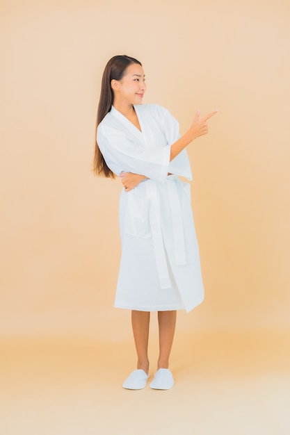 Portrait beautiful young asian woman wearing bathrobe with smile on beige