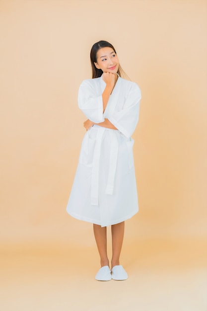 Portrait beautiful young asian woman wearing bathrobe with smile on beige